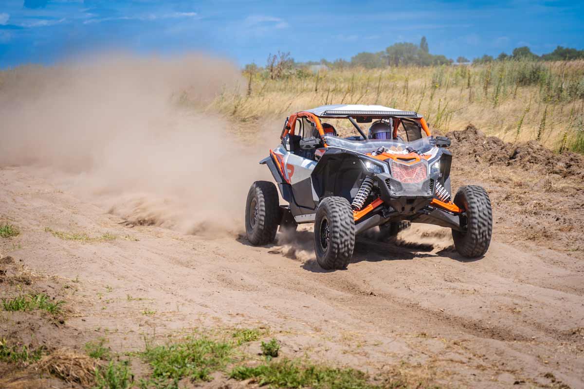 A UTV kicks up dust on a trail.